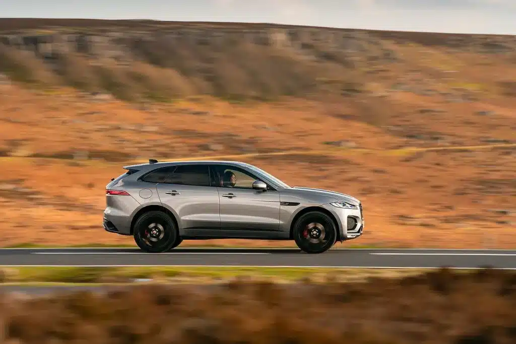 Silver luxury SUV driving on a road through a scenic desert landscape, showcasing speed and style.