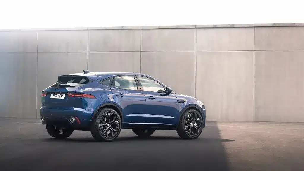 Blue SUV with sleek design parked in front of a concrete wall in sunlight.