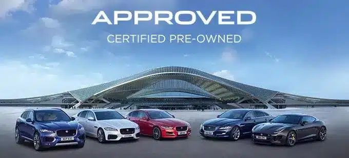 Five luxury cars displayed in front of a modern building under "Approved Certified Pre-Owned" text.